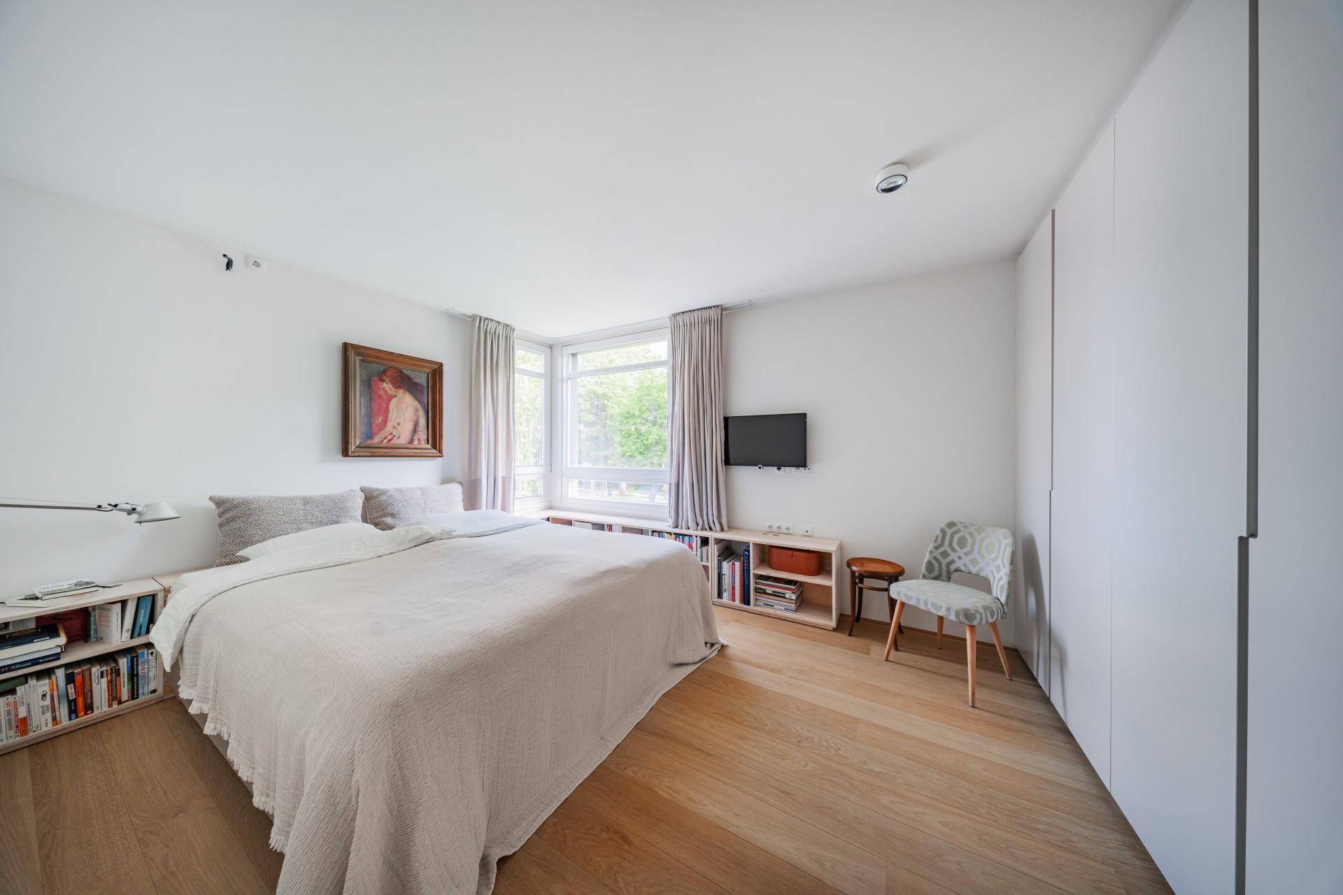 Helles Schlafzimmer mit Holzboden, Einbauschränken und großem Fenster.