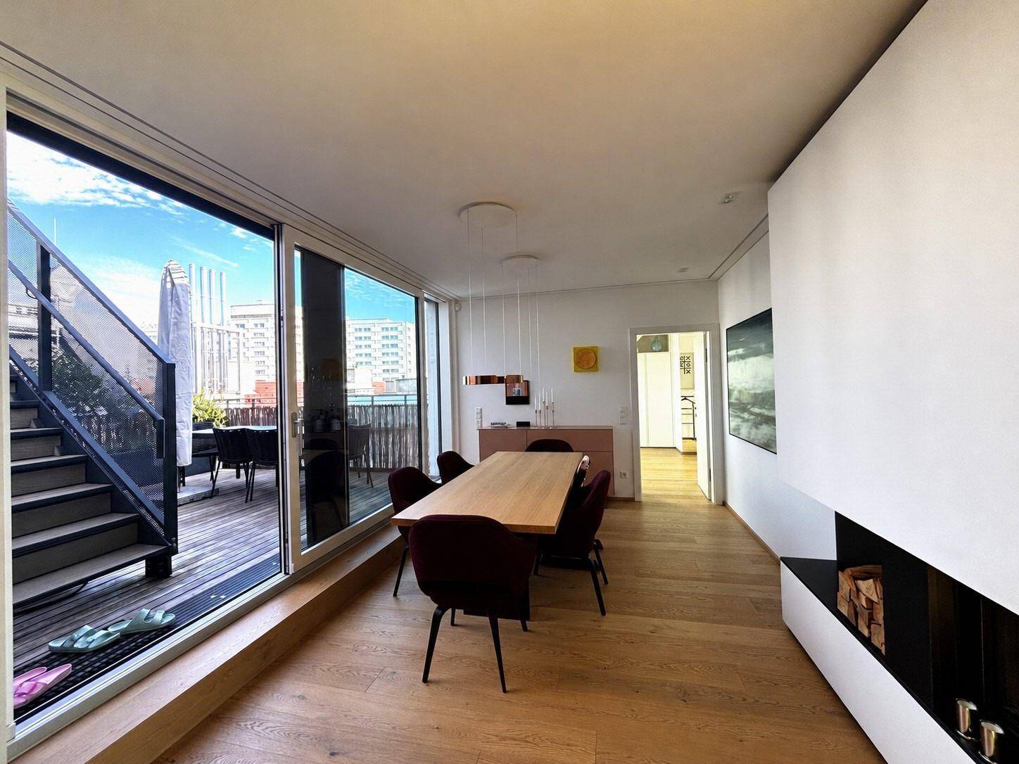 Moderner Essbereich mit Holztisch, Zugang zur Terrasse und Blick auf die Stadt.