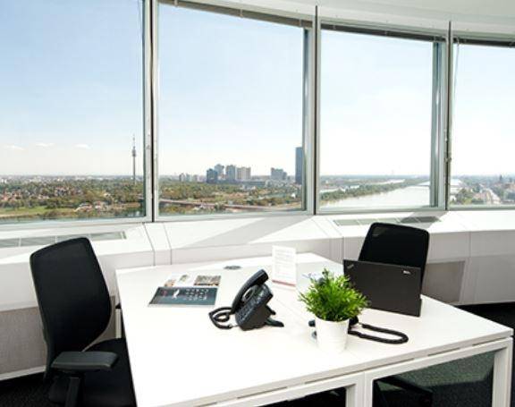 Helles Büro mit Schreibtisch, Bürostühlen und weitem Blick über die Stadt und den Fluss.
