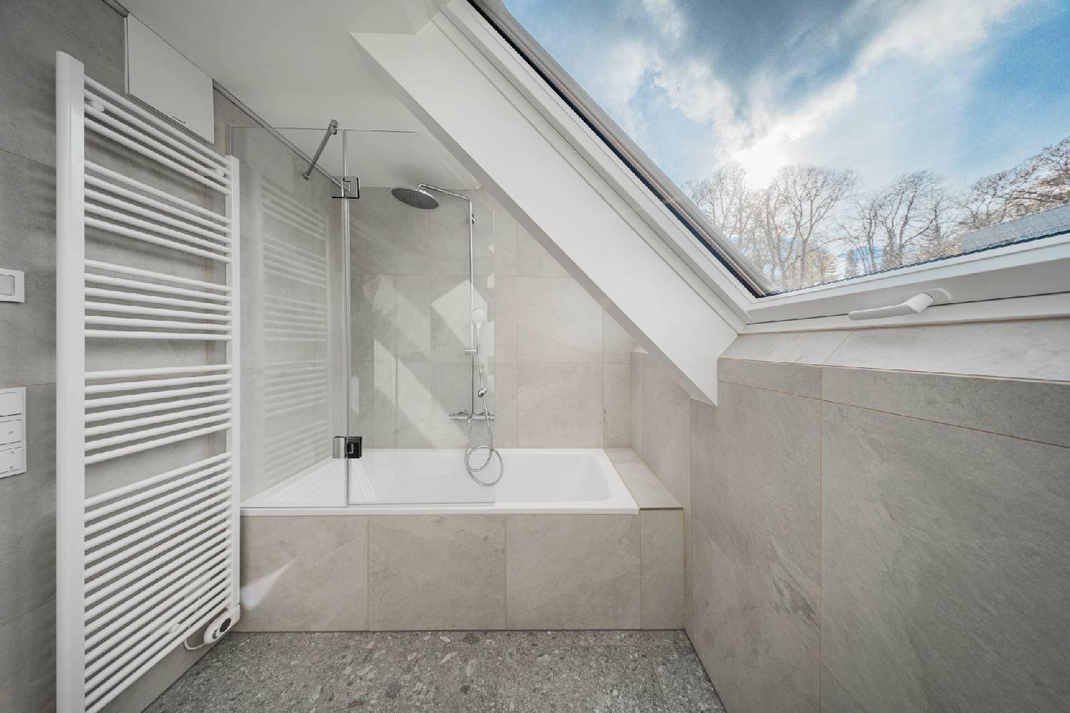 Modernes Badezimmer mit Badewanne, Dusche, Dachfenster und beheiztem Handtuchhalter.
