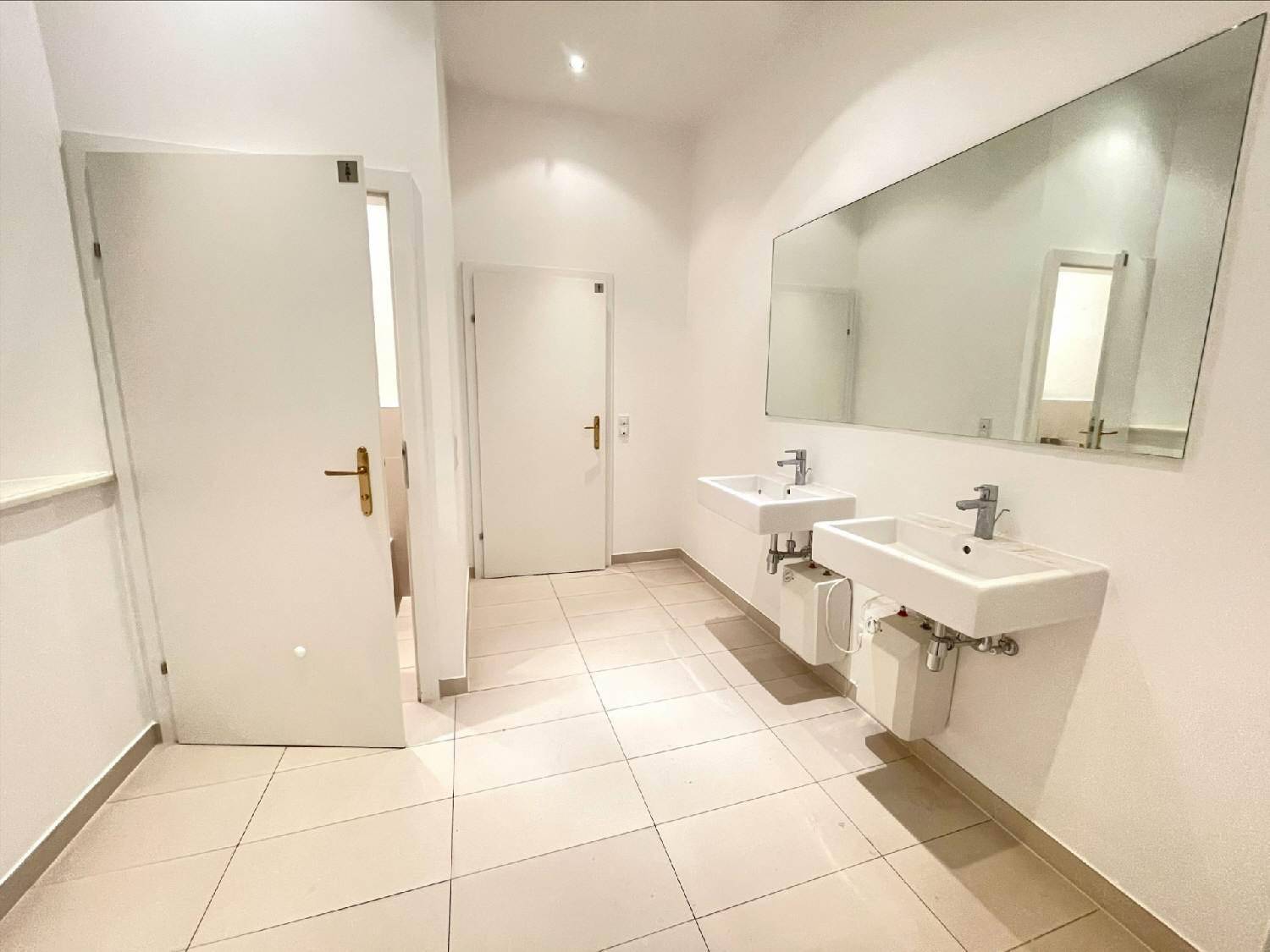Modernes Badezimmer mit zwei Waschbecken, großem Spiegel und hellen Fliesen, das viel Platz bietet.