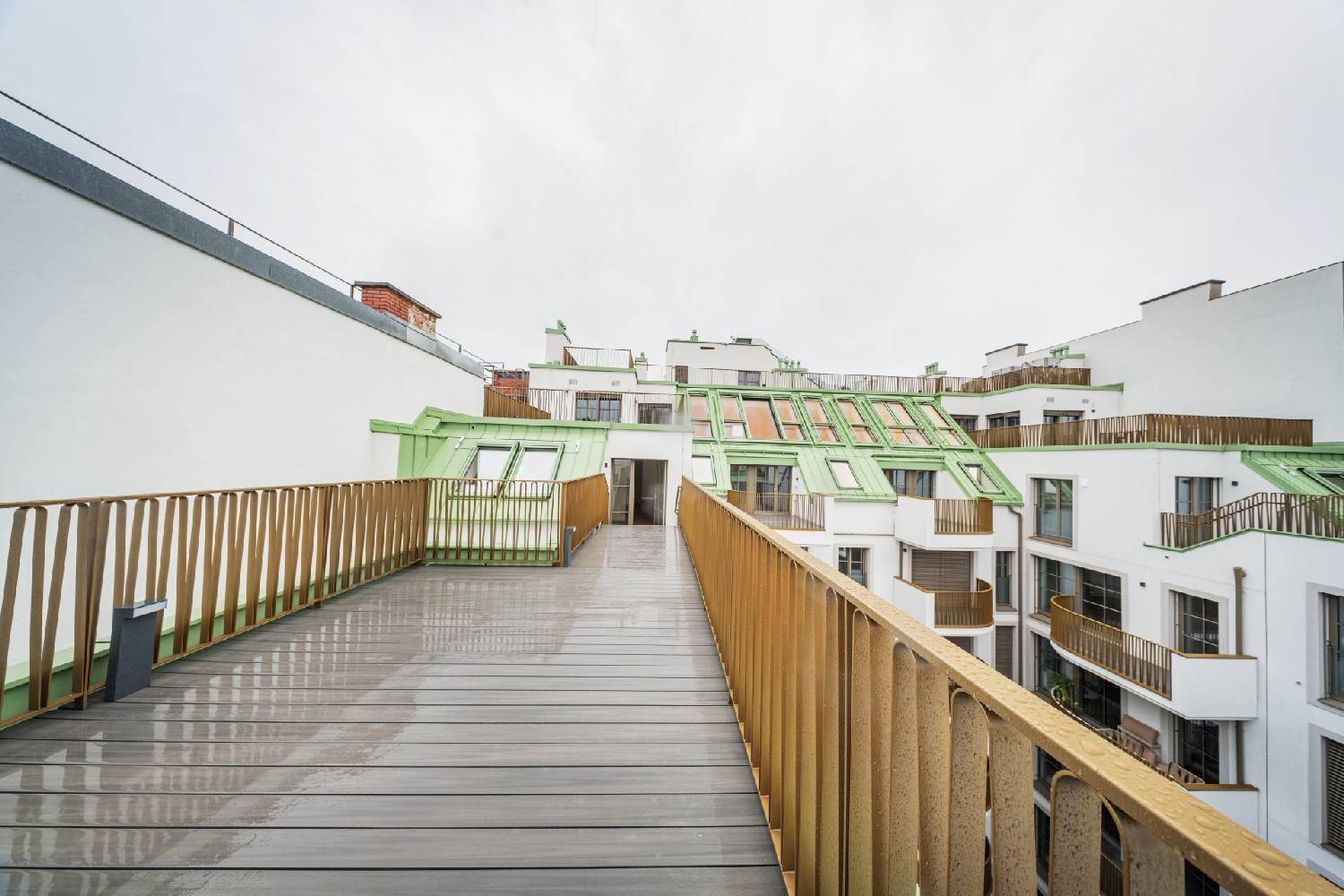Geräumige Dachterrasse mit Holzbelag und weitem Blick auf die umliegenden Gebäude der Stadt.
