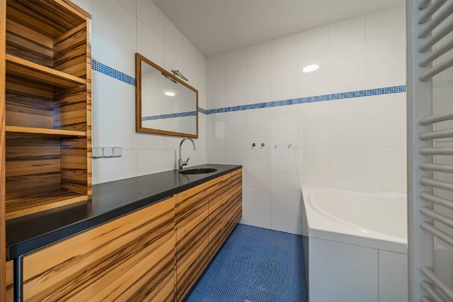 Badezimmer mit Holzwaschtisch, dunkler Arbeitsplatte und Badewanne.