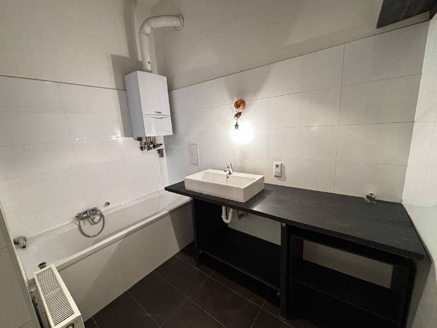 Badezimmer mit Badewanne, modernem Aufsatzwaschbecken und Gastherme an der Wand.