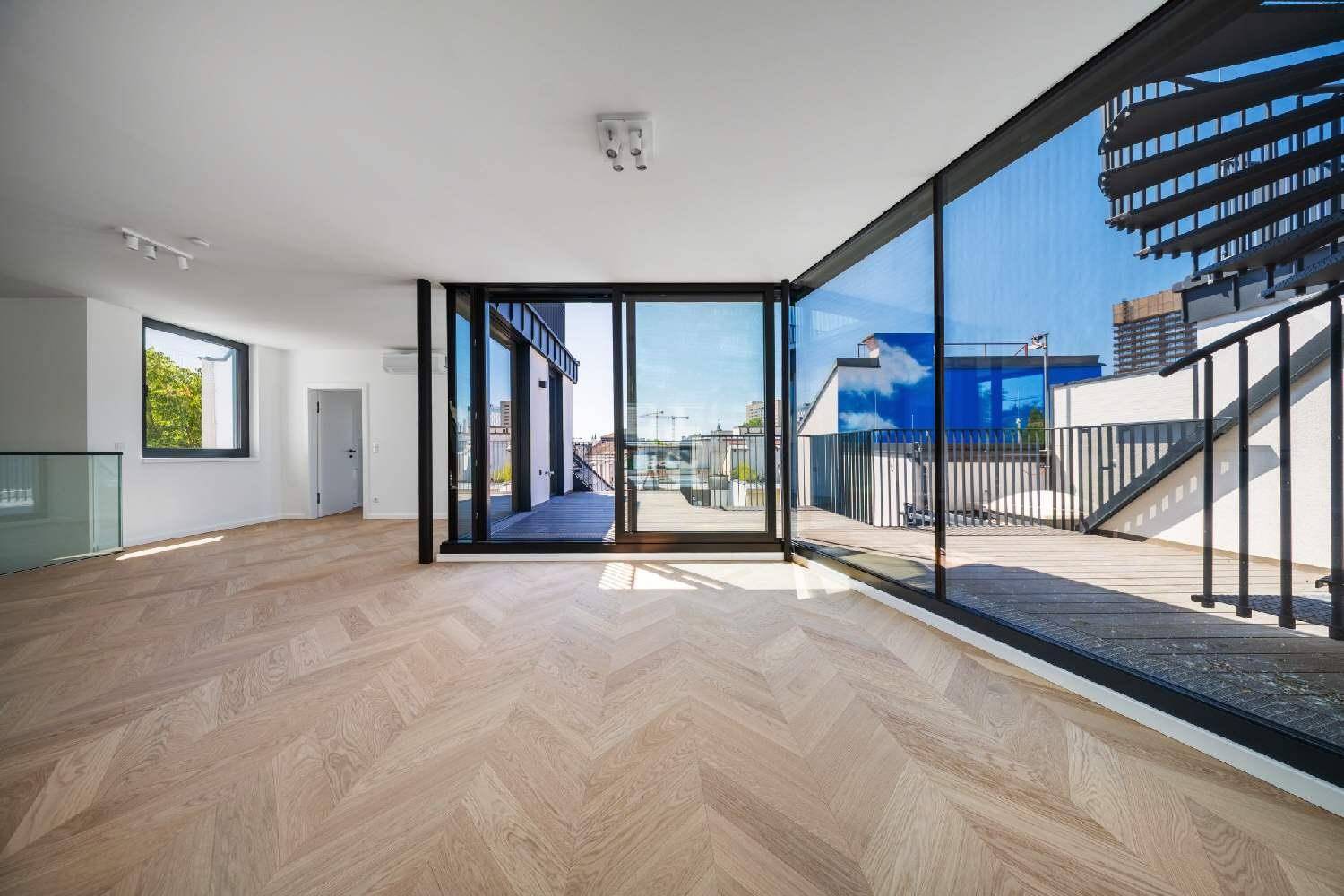 Großzügiger Wohnbereich mit raumhohen Fenstern und direktem Zugang zu einer weitläufigen Dachterrasse.