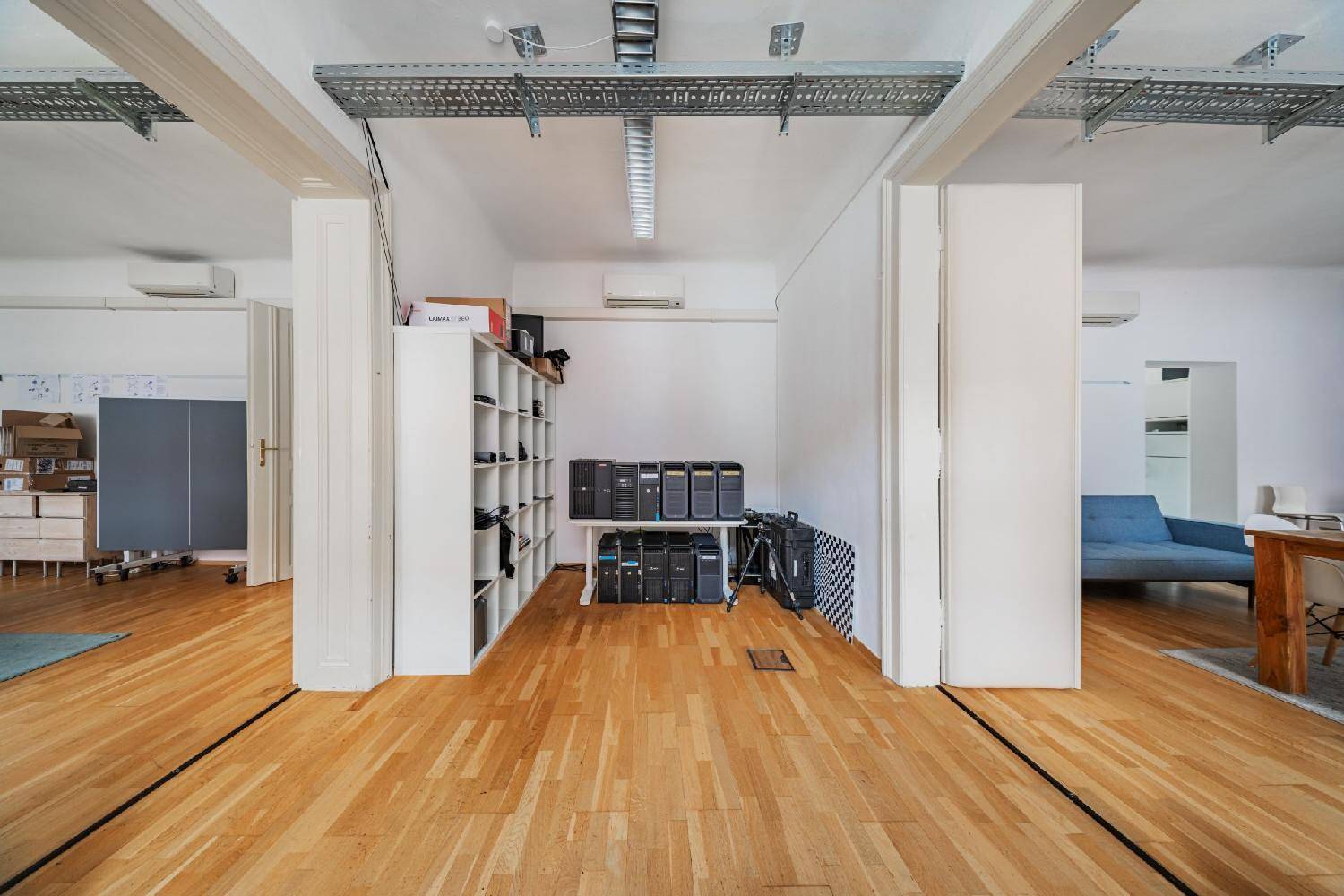 Großer Büroraum mit Holzboden, Regalen und Server-Racks, offen gestaltet.