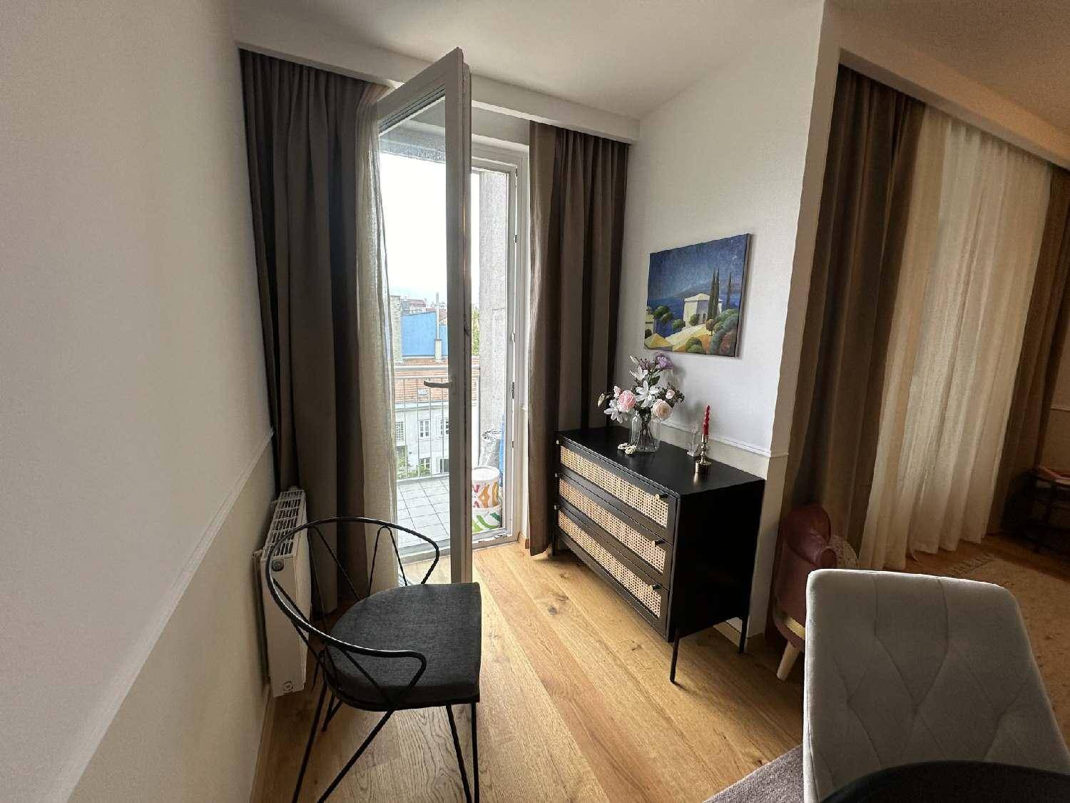 Kleiner Bereich mit Holzboden, Kommode und Zugang zu einem Balkon mit Tageslicht.