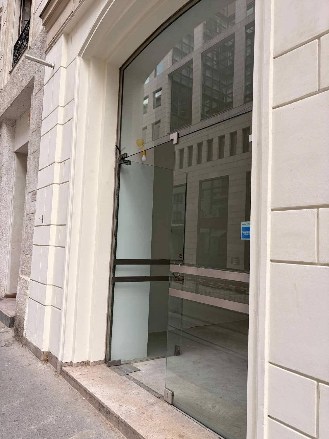 Moderne Glasfassade des Gebäudeeingangs mit reflektierenden Fenstern und weißer Verkleidung.
