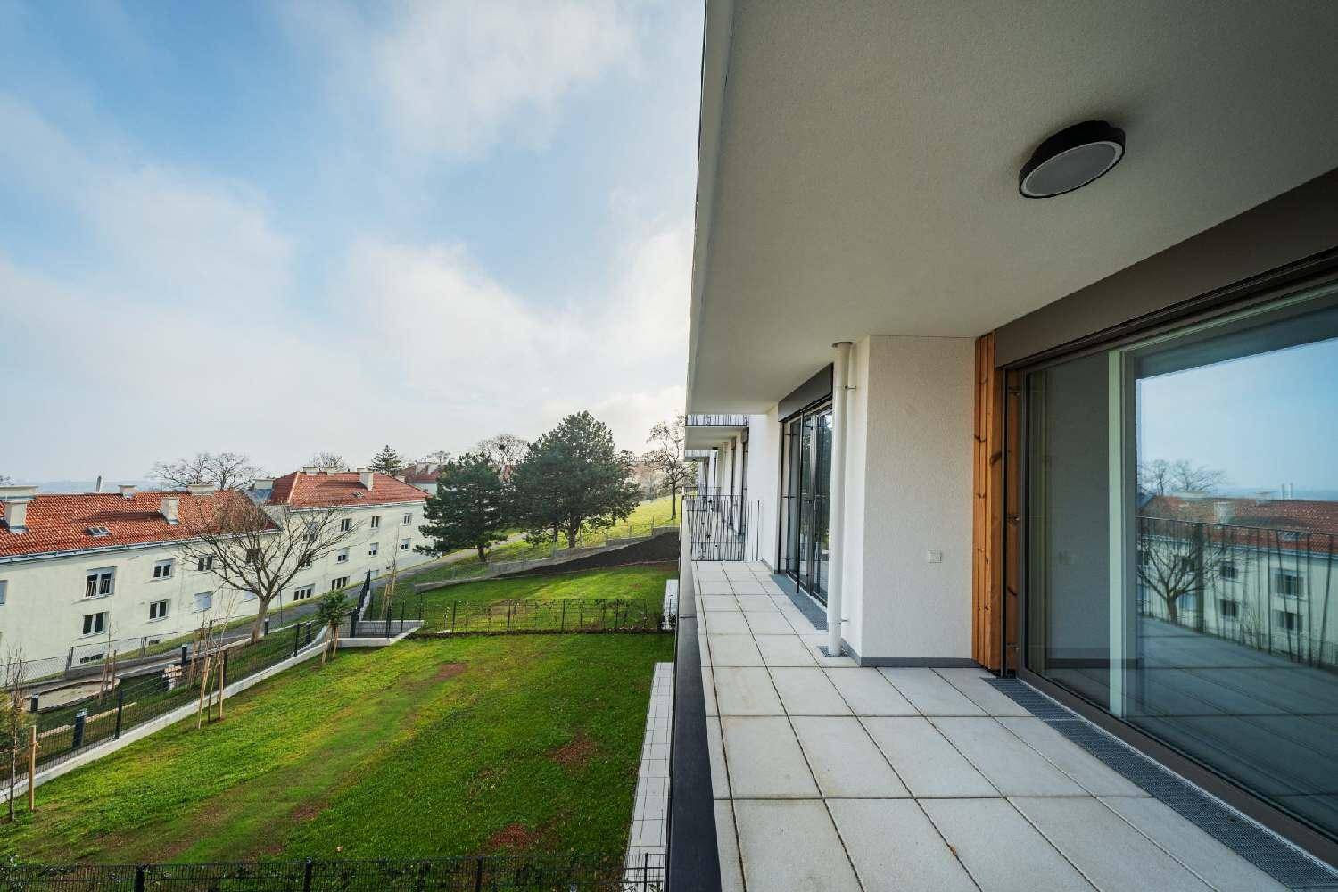 Langer Balkon mit Fliesenboden und weitem Blick über die grüne Umgebung und Dächer.