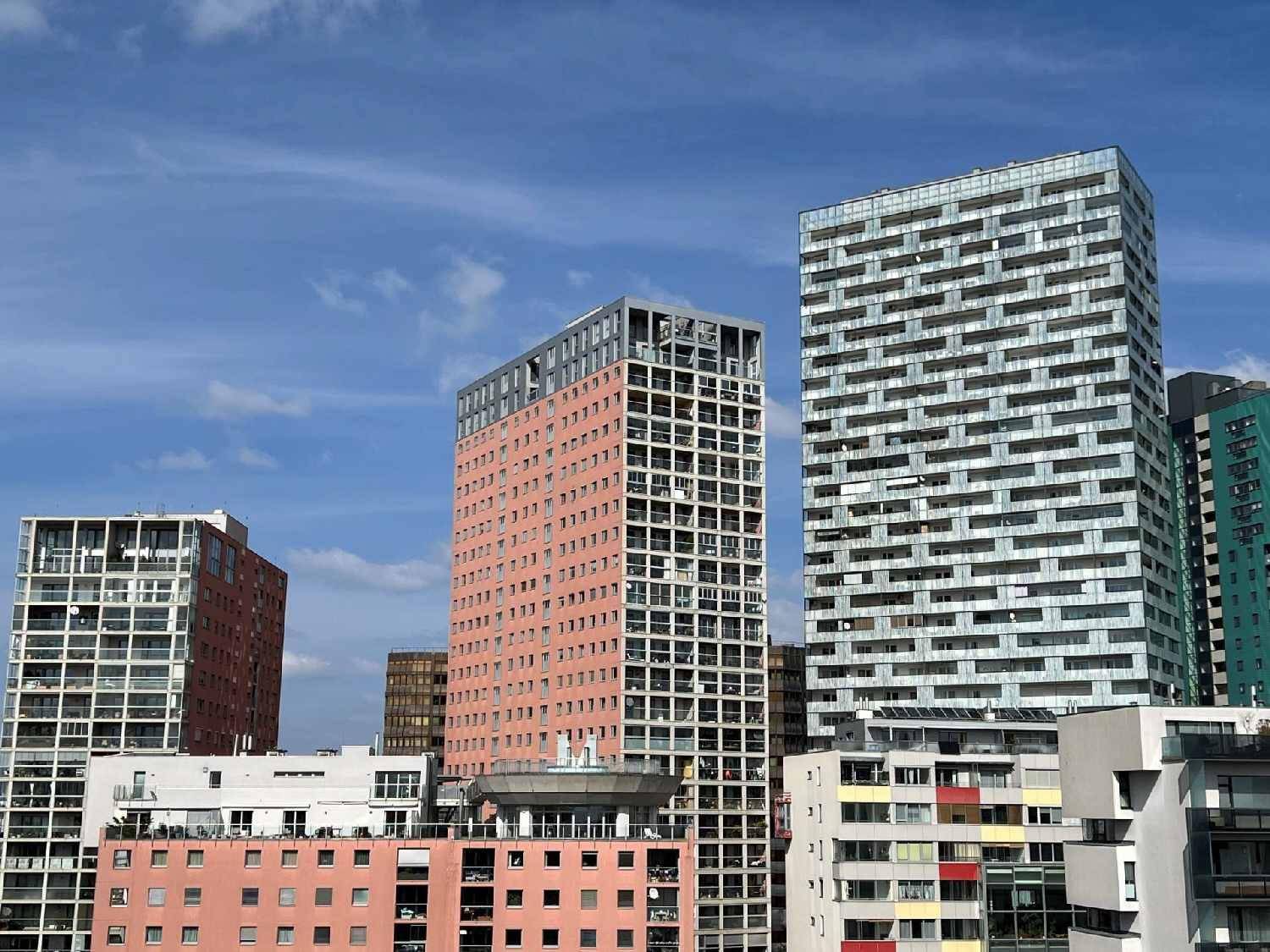 Moderne Hochhäuser mit unterschiedlichen Fassaden unter blauem Himmel.