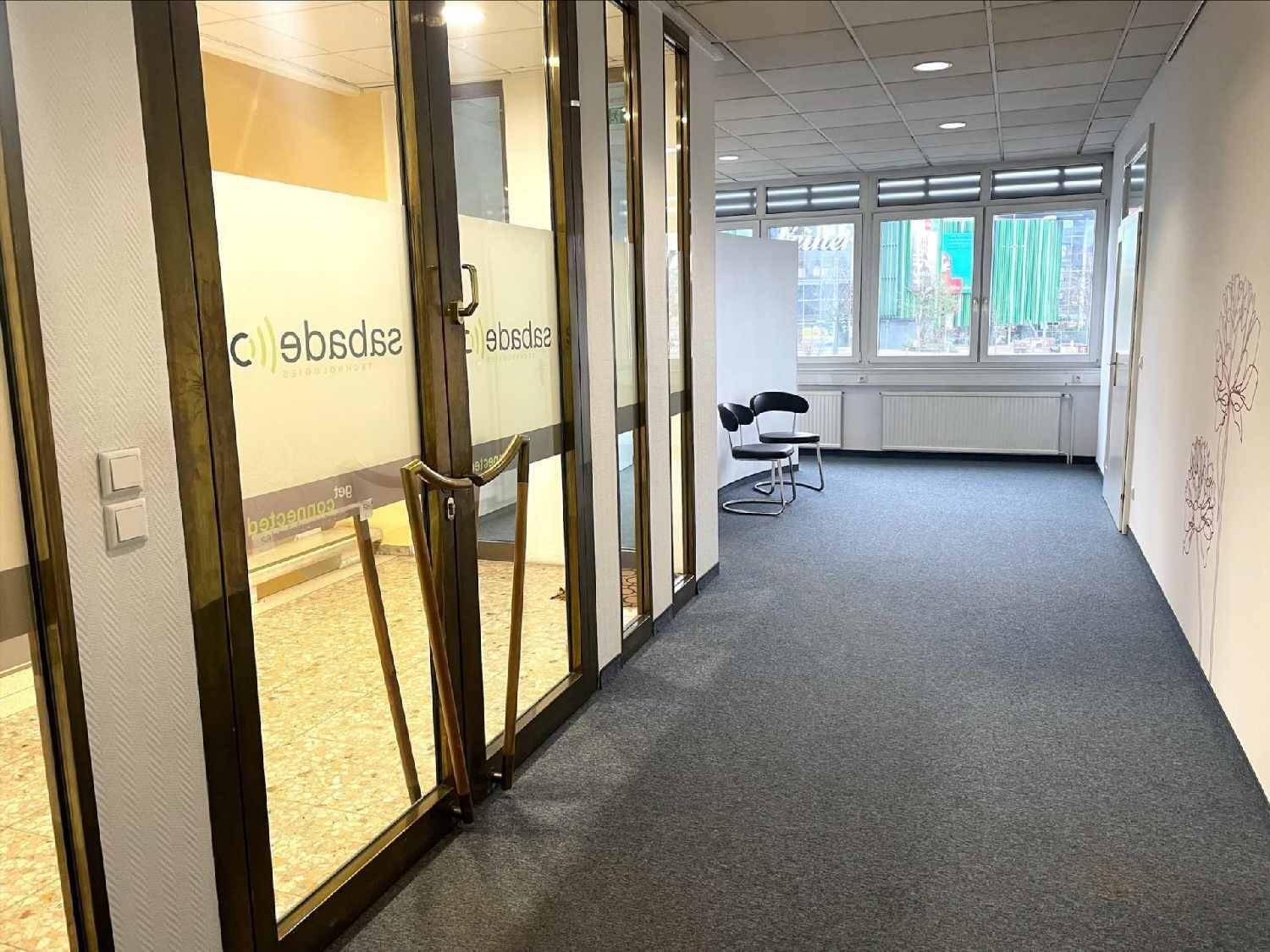 Flur mit Glasabtrennungen und dekorativer Wandzeichnung, führt zu weiteren Büroräumen.