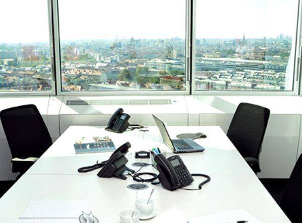 Büro mit mehreren Arbeitsplätzen, Telefonen und beeindruckendem Panoramablick auf die Stadt.