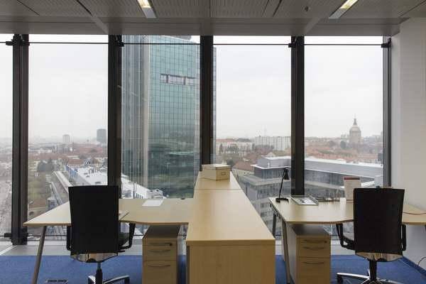 Helles Büro mit zwei Arbeitsplätzen und beeindruckendem Panoramablick auf die Stadt und umliegende Gebäude.