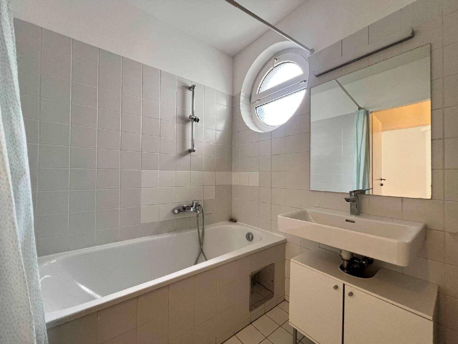 Helles Badezimmer mit Badewanne, Waschbecken, Spiegel und einem einzigartigen runden Fenster.