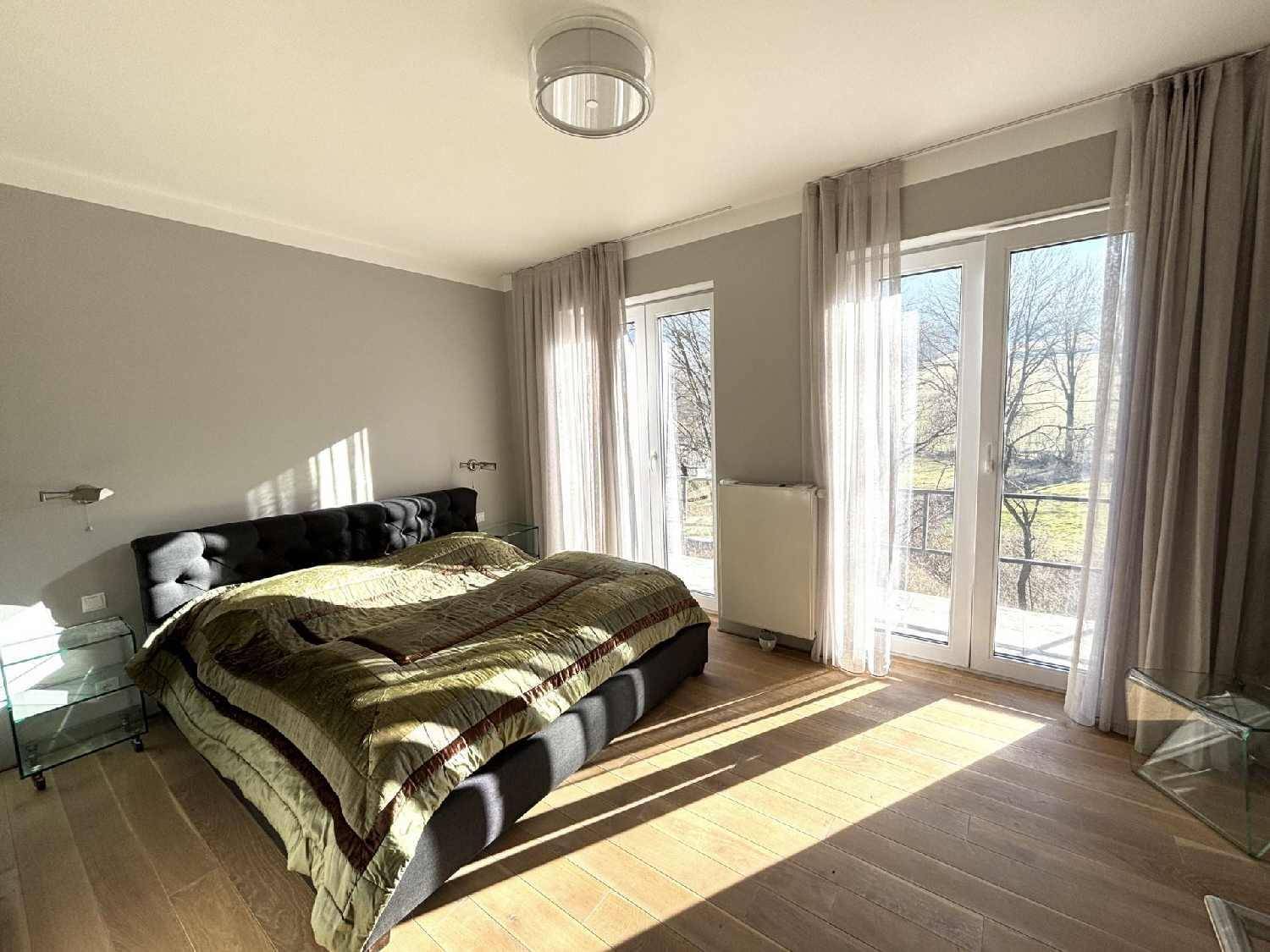 Helles Schlafzimmer mit Holzboden, Doppelbett und Balkonzugang mit Blick ins Grüne.