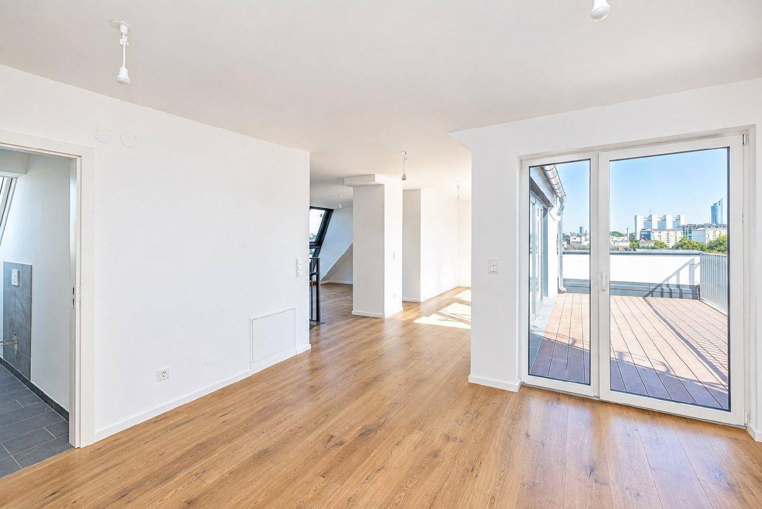 Geräumiger, heller Innenraum mit Holzboden und Zugang zu einer Dachterrasse, ideal für offenes Wohnen.