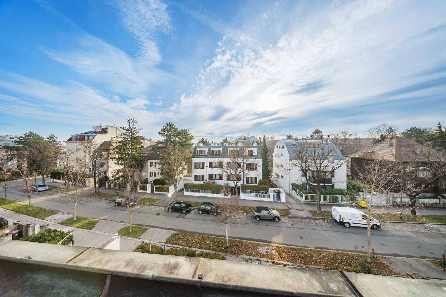 Weitläufiger Blick über die Wohnstraße mit gepflegten Häusern und Bäumen unter blauem Himmel.