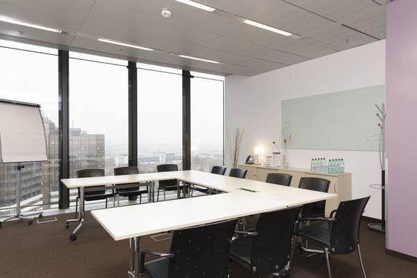 Geräumiger Konferenzraum mit U-förmigem Tisch, Whiteboard und weitem Blick über die Stadt.