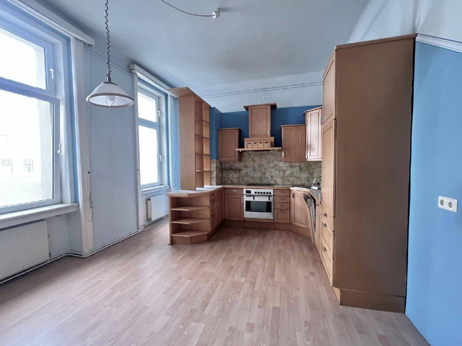 Helle Küche mit Holzschränken, blauen Wänden und Blick auf die Stadt durch große Fenster.