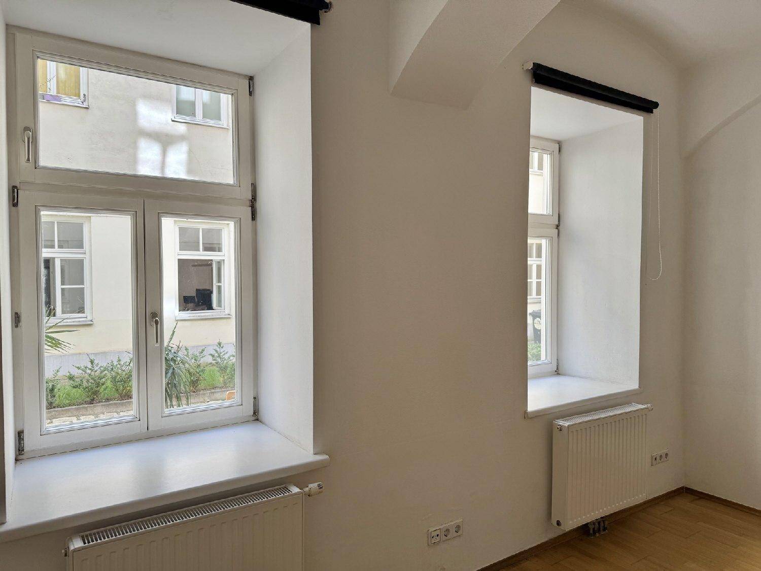 Detailansicht der Fenster mit Blick auf den begrünten Innenhof und die umliegenden Gebäude.