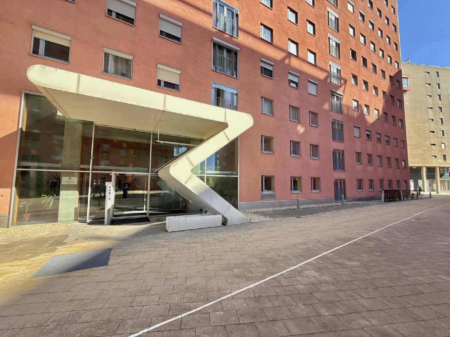 Moderner Eingangsbereich des Gebäudes mit auffälliger Architektur und Glasfront.