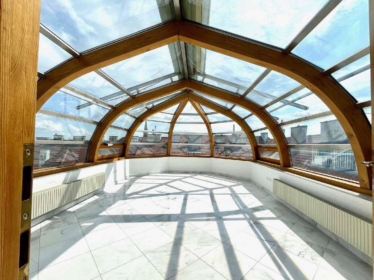 Lichtdurchfluteter Wintergarten mit beeindruckender Glaskonstruktion und Marmorboden, bietet Panoramablick.
