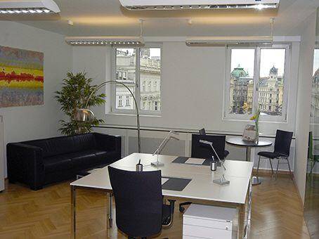 Geräumiges Großraumbüro mit mehreren Arbeitsplätzen, einem Sofa und Fenstern mit Blick auf die Stadt.