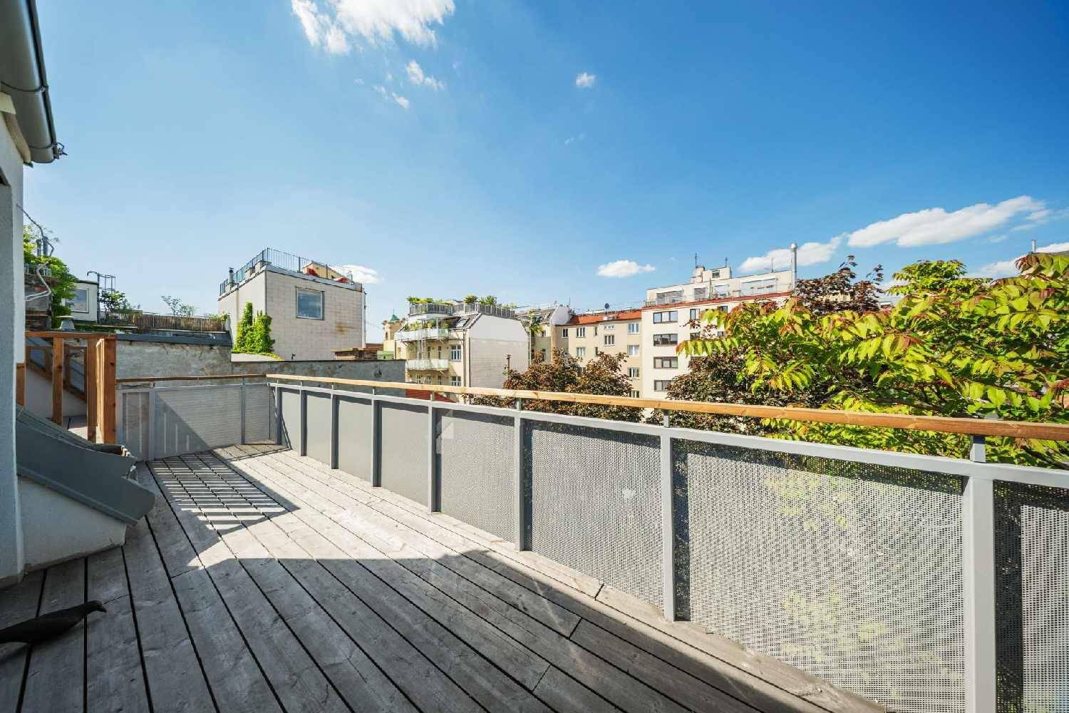 Geräumiger Holzbalkon mit Metallgeländer, bietet viel Platz und einen weiten Blick über die Stadt.