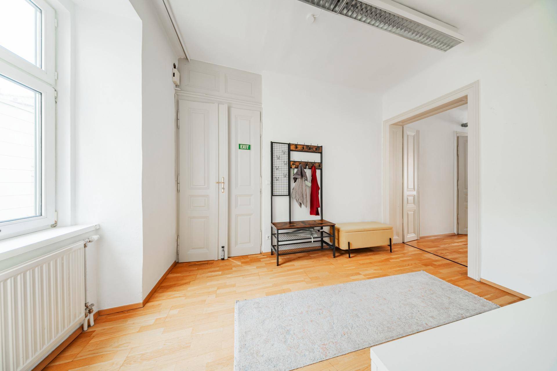 Eingangsbereich mit Holzboden, Garderobe und einem Fenster, das viel Tageslicht hereinlässt.