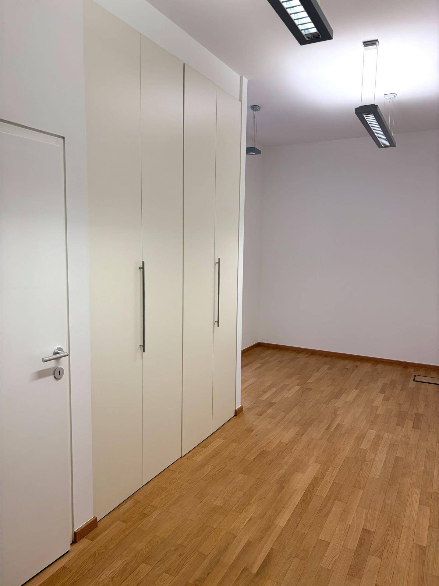 Heller Flur mit Einbauschränken in hellem Farbton und einem warmen Holzfußboden.