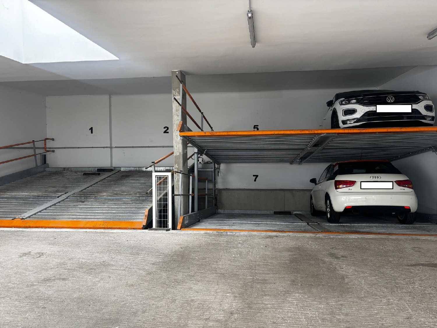 Innenansicht einer modernen Tiefgarage mit hydraulischen Parksystemen für mehrere Fahrzeuge.