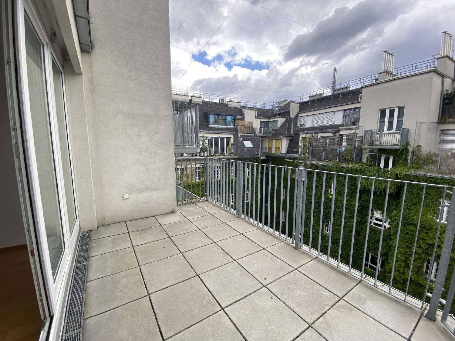 Geräumiger Balkon mit Fliesenboden und Metallgeländer, umgeben von begrünten Fassaden.