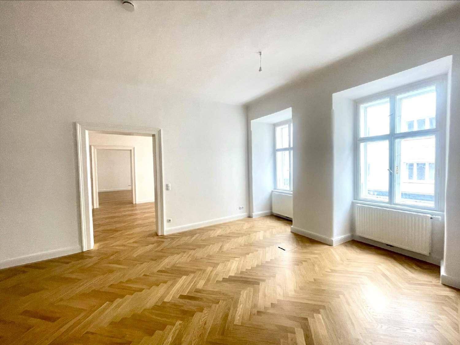 Helles Wohnzimmer mit klassischem Fischgrätparkett, hohen Decken und großen Fenstern mit Blick nach draußen.