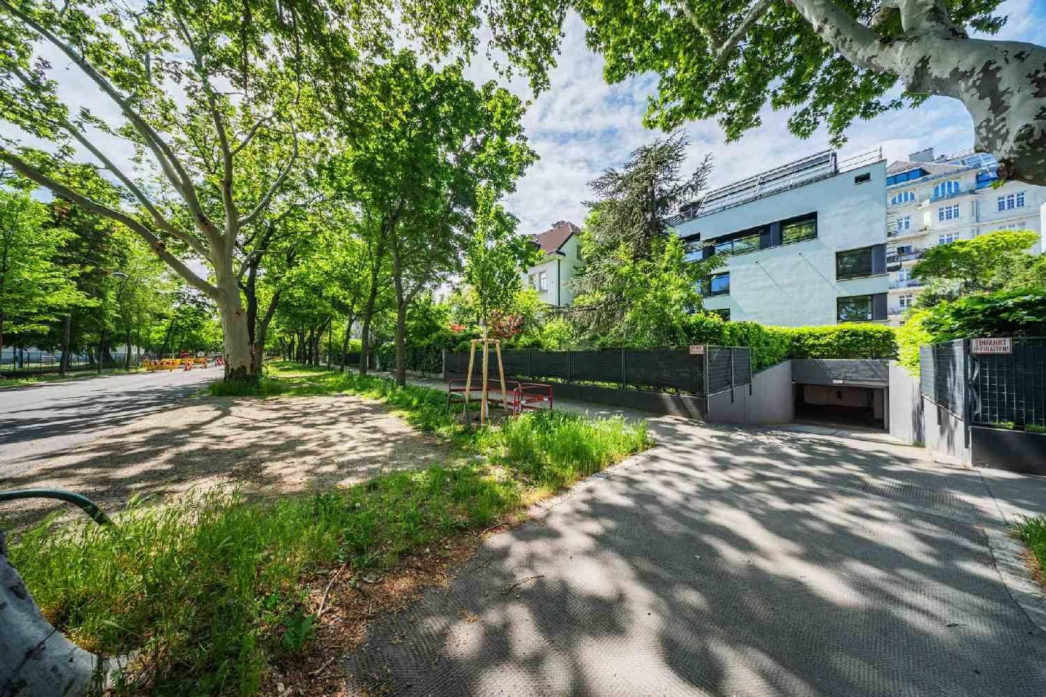 Außenansicht des Gebäudes mit Tiefgaragenzufahrt und grüner Umgebung.