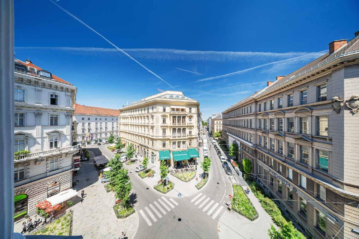 Weitläufige Stadtansicht mit Gebäuden, Straßen und blauem Himmel von oben.