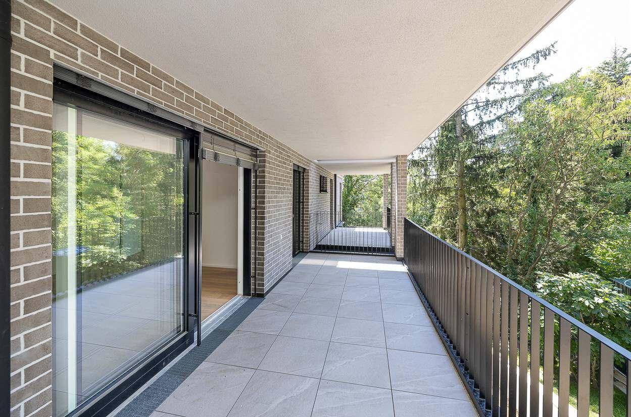 Langer Balkon mit Fliesenboden, Ziegelmauerwerk und weitem Blick ins Grüne.