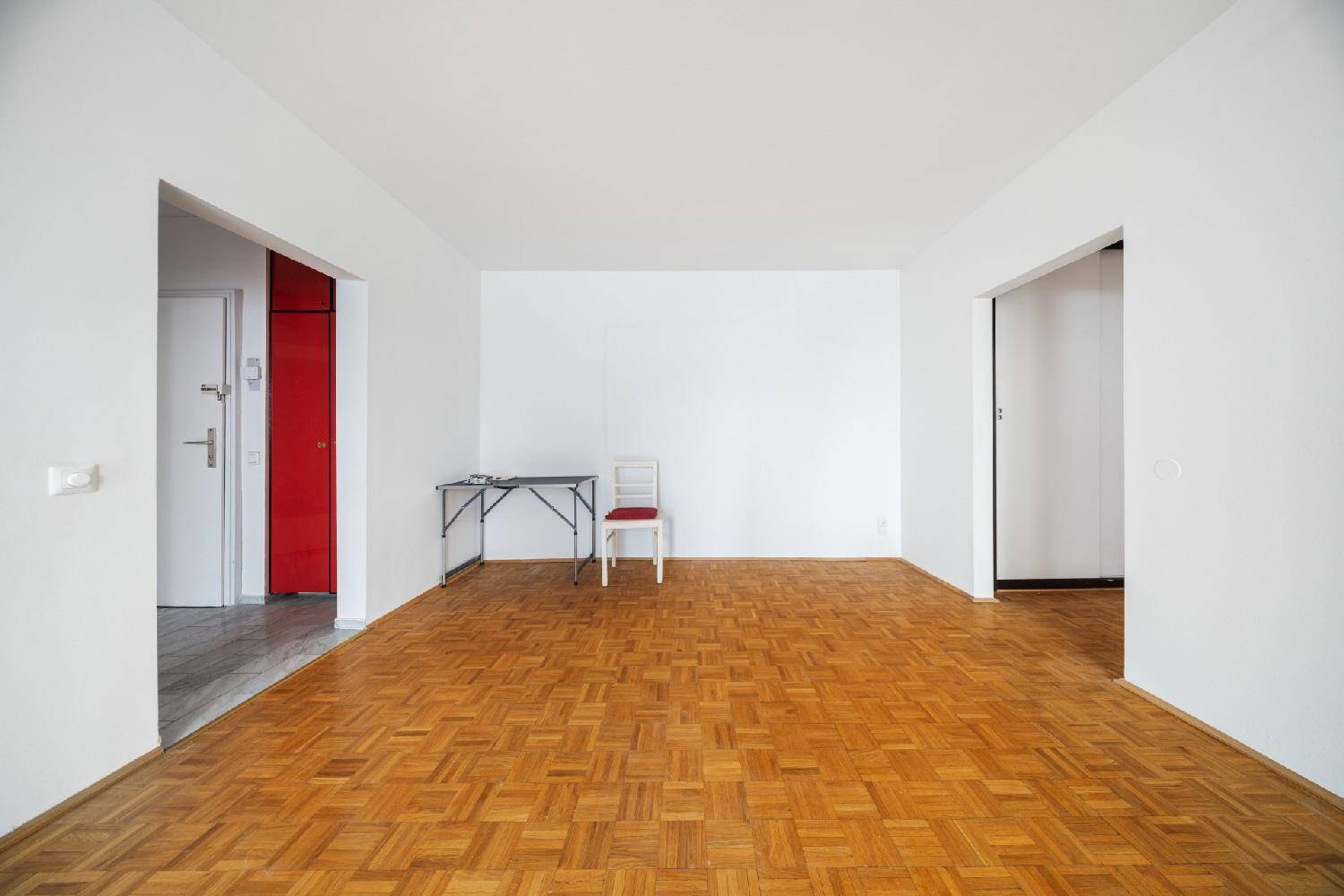 Geräumiges Zimmer mit Parkettboden und mehreren Türen, ideal für flexible Nutzung.