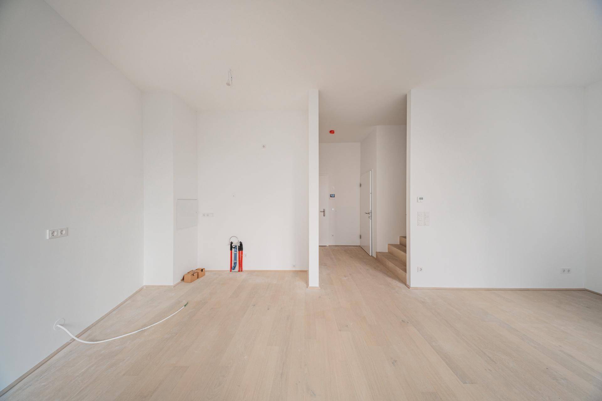 Geräumiger, heller Wohnbereich mit Holzboden und minimalistischem Design, bereit zur Einrichtung.