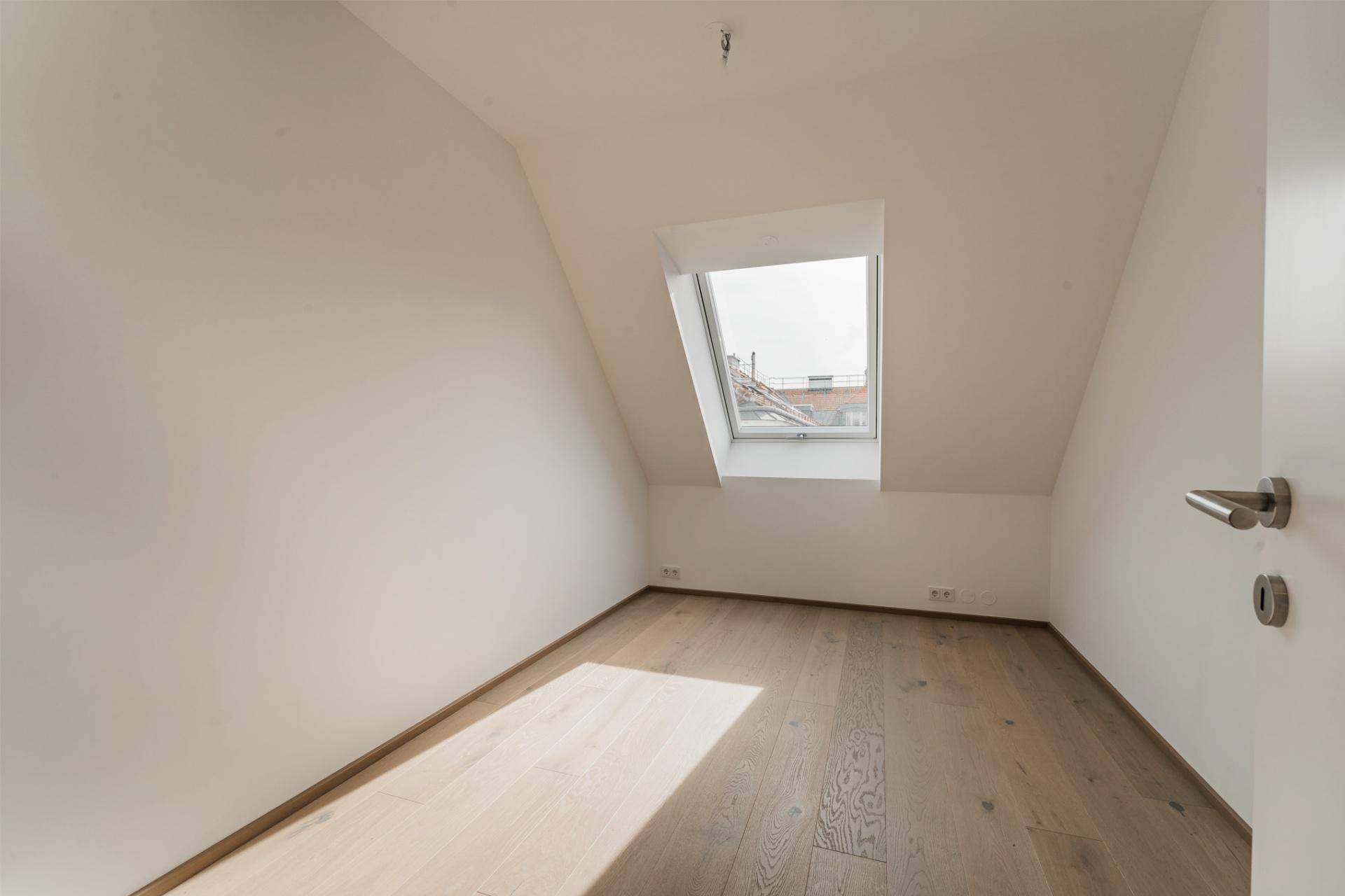 Helles Schlafzimmer mit Holzboden und Dachfenster, ideal für ein gemütliches Ambiente.