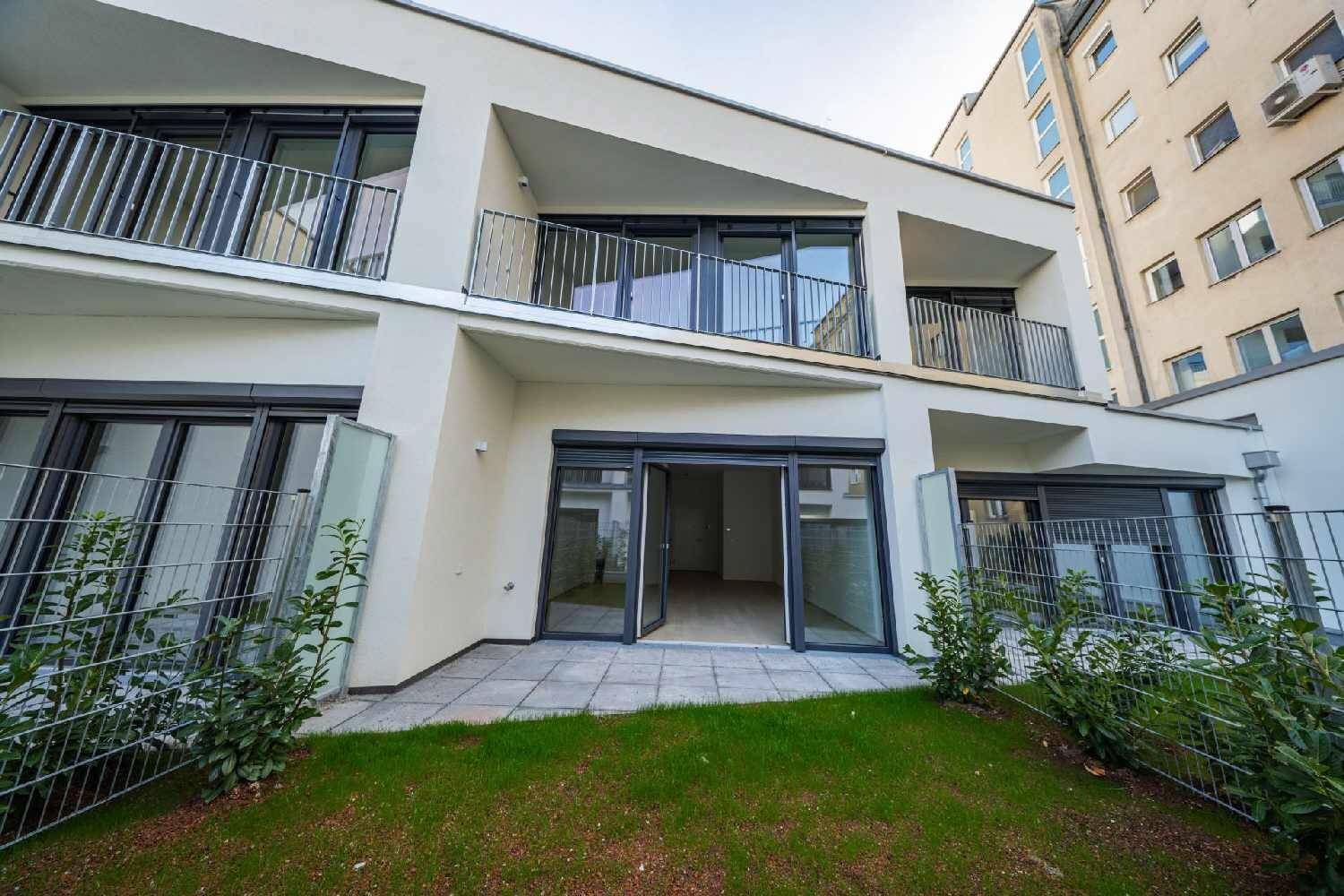 Moderne Gebäudefassade mit großen Fenstern und direktem Zugang zur Terrasse und zum Garten.