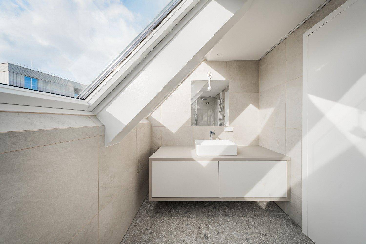 Helles Badezimmer mit modernem Waschtisch, Einzelwaschbecken und großem Dachfenster.