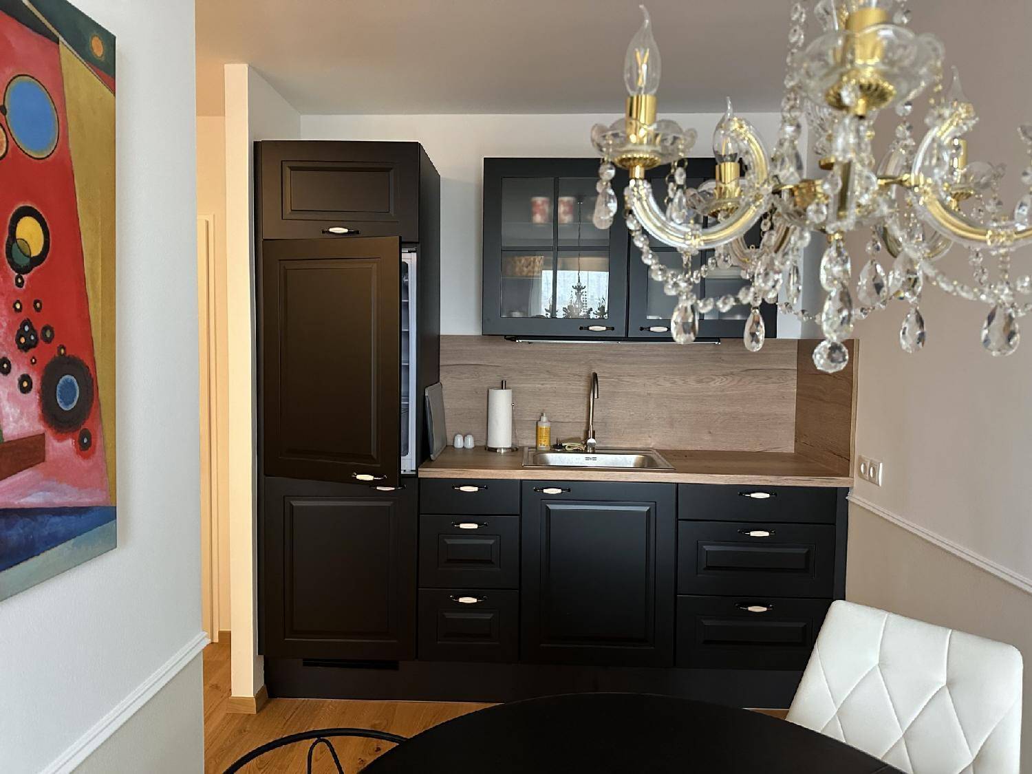 Moderne Einbauküche in Schwarz mit Holzarbeitsplatte, Spüle und integriertem Kühlschrank.