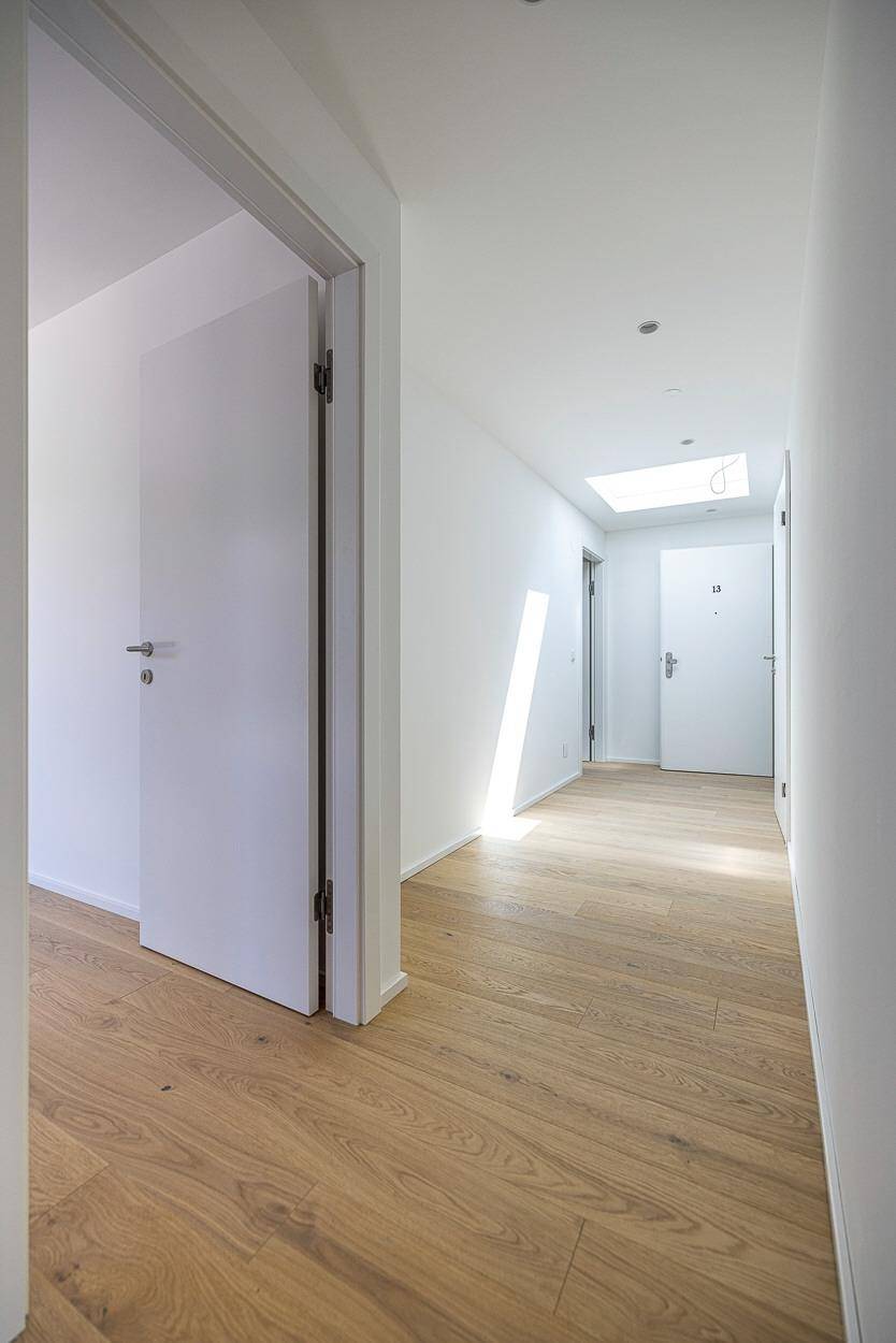 Heller Flur mit Holzboden und mehreren Türen, führt zu verschiedenen Räumen.