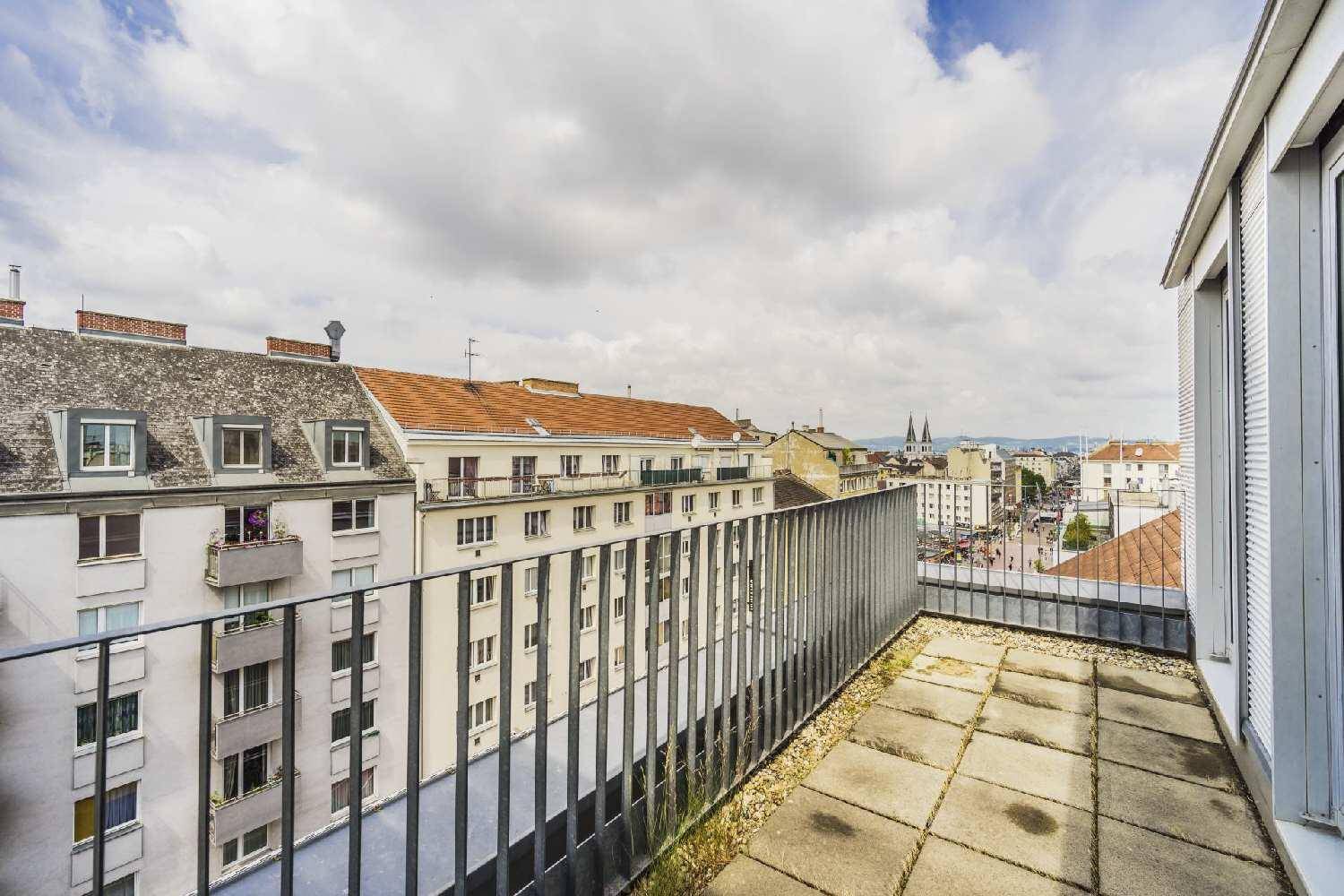 Dachterrasse mit Fliesenboden und Metallgeländer, bietet einen weiten Blick über die Stadt.