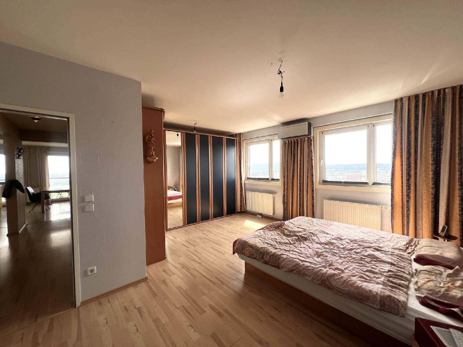 Schlafzimmer mit Holzboden, großem Bett, Einbauschränken und Fenstern, die einen weiten Blick bieten.