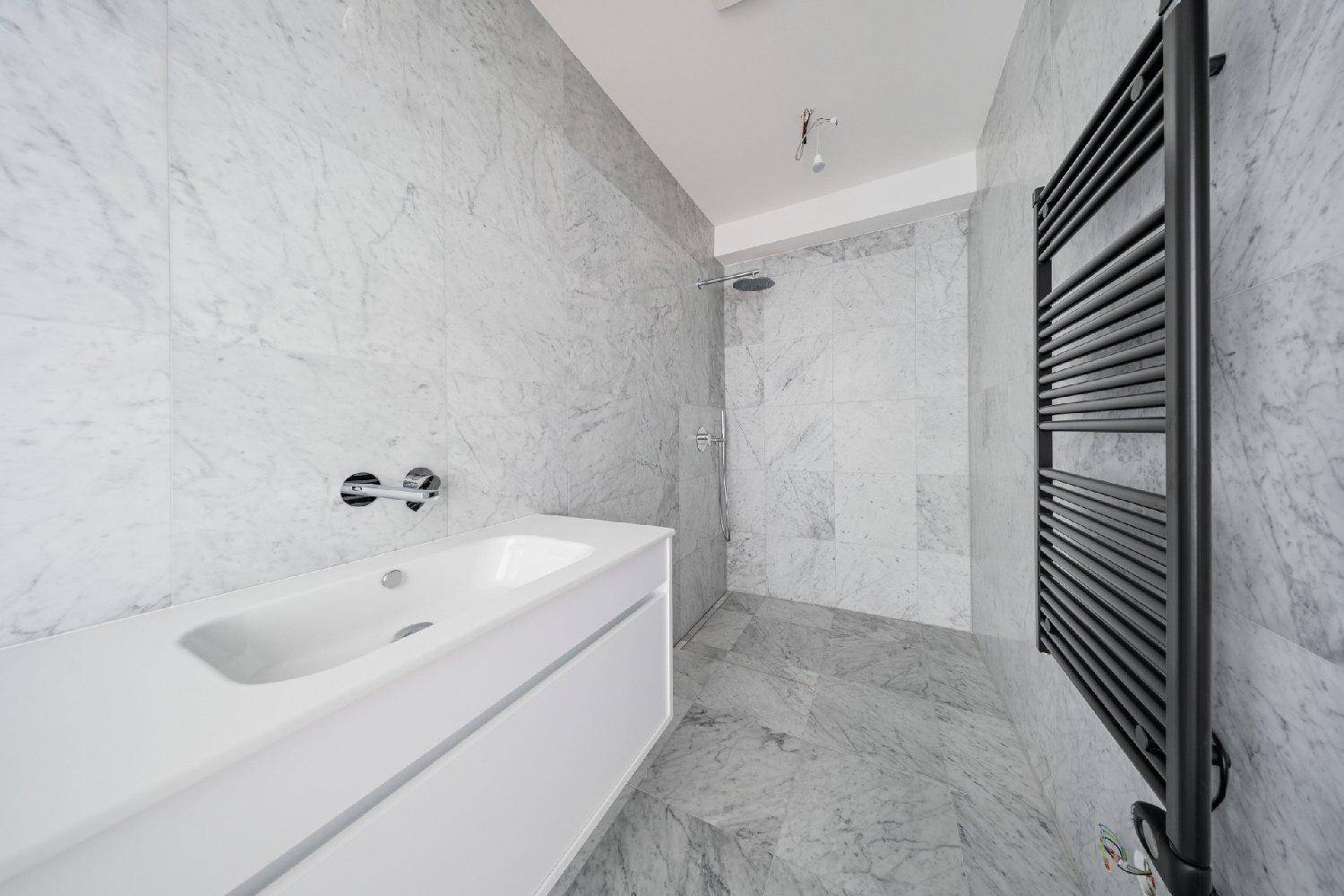 Modernes Badezimmer mit Marmorfliesen, begehbarer Dusche und beheiztem Handtuchhalter.