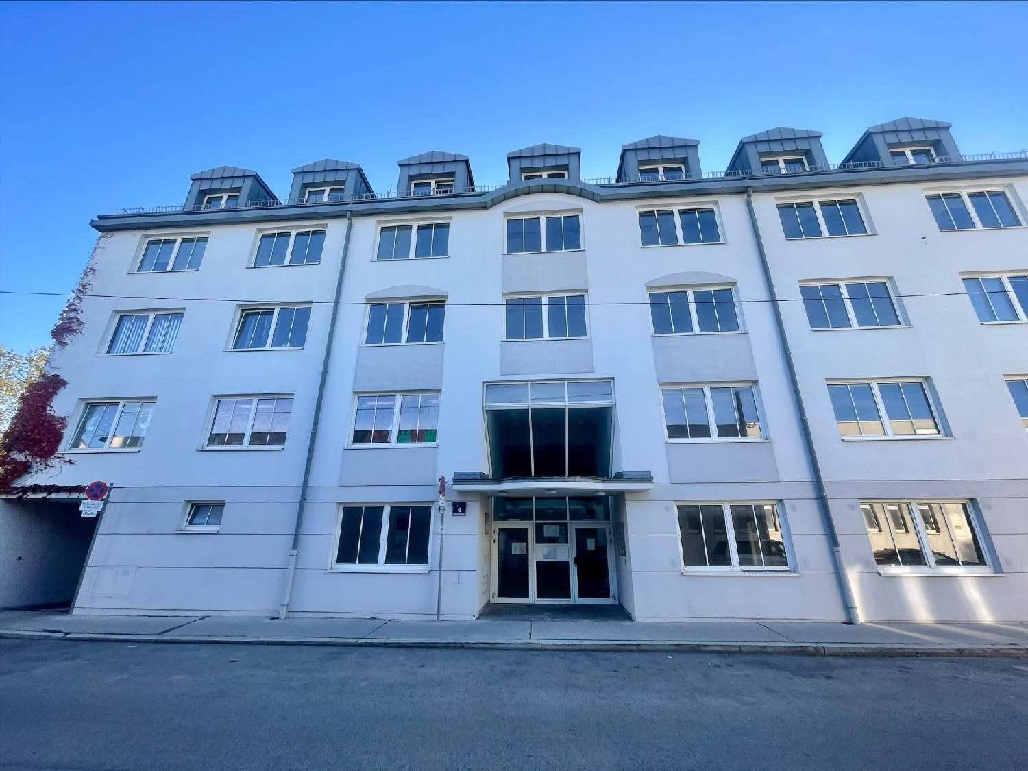 Mehrstöckiges Gebäude mit vielen Fenstern und Dachgauben unter blauem Himmel, das eine solide Architektur zeigt.
