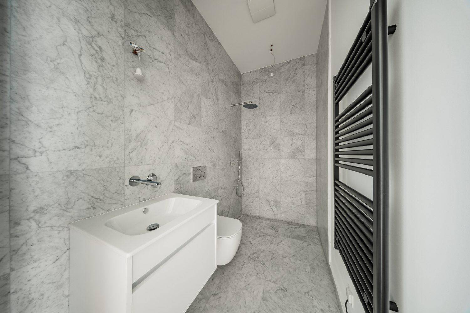 Modernes Badezimmer mit Marmorfliesen, Dusche, Einzelwaschbecken und beheiztem Handtuchhalter.