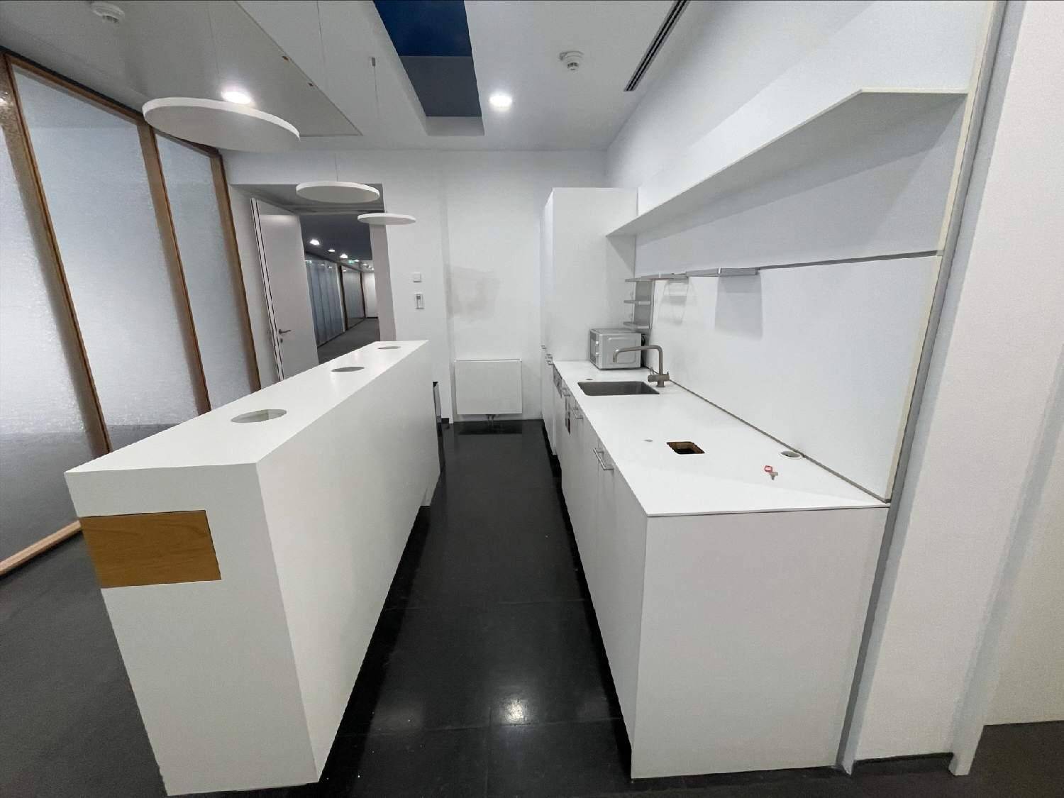 Moderne Teeküche mit weißen Schränken, Spüle und Mikrowelle, ideal für Pausenbereiche im Büro.