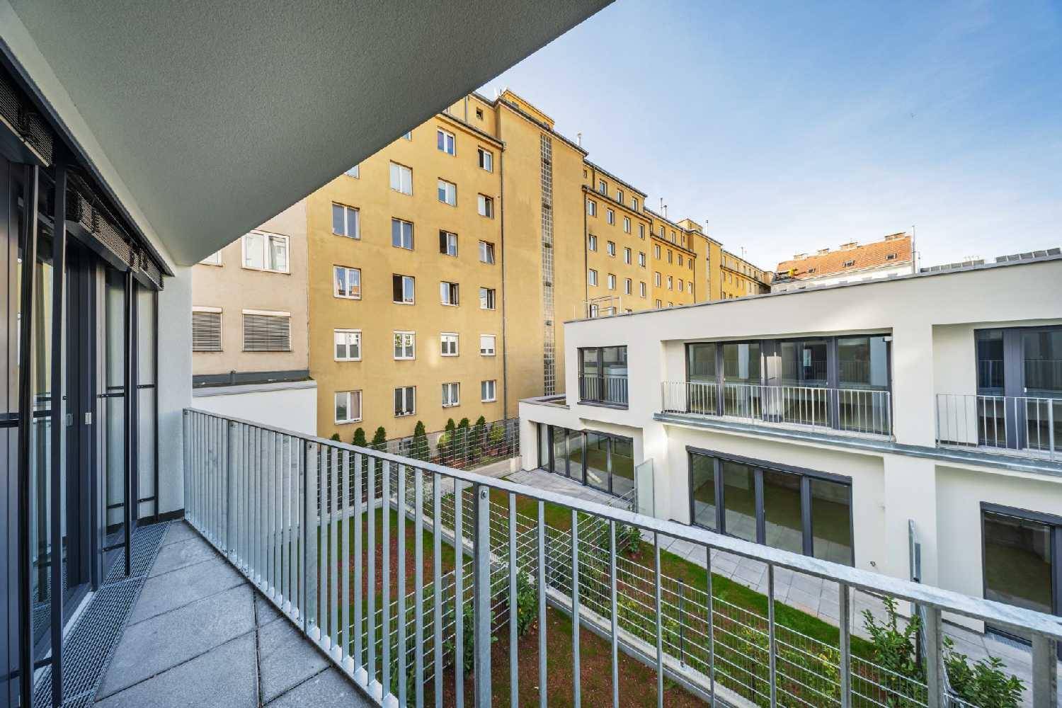 Moderner Balkon mit Metallgeländer und Blick auf den begrünten Innenhof und umliegende Gebäude.